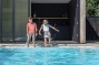 kindjes spelen naast een strak wit zwembad bij moderne villa