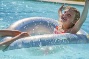 kind speelt in het water van een strak wit zwembad bij moderne villa